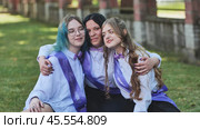 Three happy graduates in sashes share a heartfelt goodbye on their last day of school, celebrating academic success with joy and excitement. Стоковое фото, фотограф Mikhail Davidovich / Фотобанк Лори
