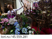 03.03.2023, Москва,  Выставка-продажа «Пассаж в цветах» в Петровском Пассаже. Девушка-флорист помогает посетительнице выставки выбрать букет. Редакционное фото, фотограф Дмитрий Киселёв / Фотобанк Лори