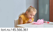 A little girl paints her lips with baby cosmetics. The child paints his lips with red lipstick. Daughter imitates her mother. Стоковое фото, фотограф Кутина Татьяна / Фотобанк Лори