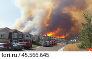 Firefighters intervening in a wildfire burning near residential houses. Стоковое AI-изображение, AI-художник Юрий Поздников / Фотобанк Лори