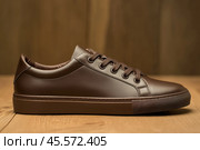 Dark brown leather lace-up running shoes with low tops, thick soles. The laces and black rubber outsole. Sporty look. Men to wear during outdoor activities, hiking. Brown shoes. Trendy Male Boot Side. Стоковое AI-изображение, AI-художник Марина Демидюк / Фотобанк Лори