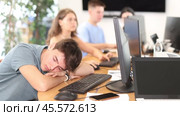 Exhausted young employee engaged in software development at IT startup in coworking space sleeping at workplace due to intensive work. Стоковое видео, видеограф Яков Филимонов / Фотобанк Лори