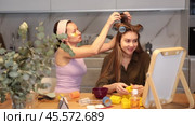 Two close female friends enjoying joint moment of beauty routine at home, with one applying hair rollers to other hair at table in front to vanity mirror. Стоковое видео, видеограф Яков Филимонов / Фотобанк Лори