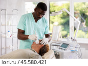 African American cosmetologist performing facial cryotherapy procedure on man. Стоковое фото, фотограф Яков Филимонов / Фотобанк Лори