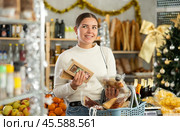 Girl shopper selects sweet nougat and panellets in grocery section of a supermarket for gifting and celebrating Christmas. Стоковое фото, фотограф Яков Филимонов / Фотобанк Лори