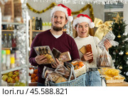 Preparing for Christmas celebration - happy family buys nougat, panettone, marzipan, panellets. Стоковое фото, фотограф Яков Филимонов / Фотобанк Лори