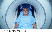 A middle-aged man lies inside an MRI machine. Стоковое AI-изображение, AI-художник Александр Довянский / Фотобанк Лори