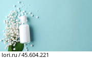 Homeopathic globules scatter alongside a glass bottle on a soothing blue background, highlighting their role in alternative healthcare and wellness solutions. Стоковое AI-изображение, AI-художник Sergey Grishin / Фотобанк Лори