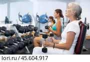 Mature sportswoman doing exercises with a barbell and dumbbells in gym. Стоковое фото, фотограф Яков Филимонов / Фотобанк Лори