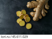 Fresh Raw Ginger Root with Cut Sections Displayed on a Dark Gray Concrete Background for Natural Detox Ingredient and Cooking Use in Culinary Arts. Whole Ginger root with textured skin and cut slices. Стоковое AI-изображение, AI-художник Марина Демидюк / Фотобанк Лори