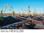 Горы угля в морском порту, грузовые вагоны из под угля, телескопические ленточные транспортеры, которые перераспределяют уголь по участку. Стоковое фото, фотограф Павел Просянов / Фотобанк Лори