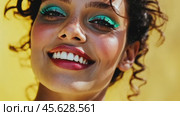 Joyful expression of a woman with vibrant makeup against a bright yellow background. Стоковое AI-видео, аниматор Sabyna75 / Фотобанк Лори