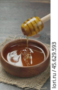 Drops of honey slowly flowing from a wooden honey dipper into a honey bowl, close-up. Honey flowing from a wooden honey dipper on to holland waffles. Vertical video. Стоковое видео, видеограф Андрис Салминьш / Фотобанк Лори