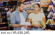 Couple man and woman choosing paint rollers and brushes. Стоковое видео, видеограф Яков Филимонов / Фотобанк Лори