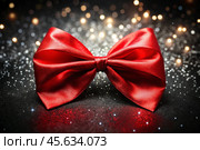 Elegant bow made of satin red ribbon on a shiny black background. Стоковое AI-изображение, AI-художник Photojuli / Фотобанк Лори