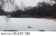 Capture the magic of the first snow falling on an empty autumn park and a frozen pond. calm and seasonal atmosphere is required. Стоковое видео, видеограф Ярославский Максим / Фотобанк Лори