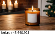 A mock-up of a cozy burning candle made of amber glass with an empty white label in a festive, New Year's home interior. Стоковое AI-изображение, AI-художник Photojuli / Фотобанк Лори