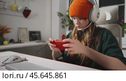 Teenage gamer immersed in focused gaming session showcases growing trend of mobile gaming among youth. With ergonomic setup and smartphone in hand, this online experience highlights world of gaming. Стоковое видео, видеограф Енваев Андрей / Фотобанк Лори