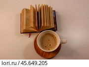 Нежное тепло кофе с пенкой, вечная мудрость книги, спокойная пауза. Стоковое фото, фотограф Hanna Shapialevich / Фотобанк Лори