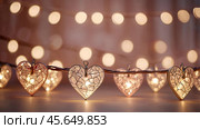 The concept of Valentine's Day, a banner with garlands in the form of hearts and magic lights for a holiday filled with love. A place for the text. Стоковое AI-изображение, AI-художник Photojuli / Фотобанк Лори