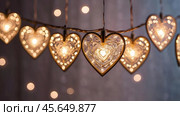 The concept of Valentine's Day, a banner with garlands in the form of hearts and magic lights for a holiday filled with love. A place for the text. Стоковое AI-изображение, AI-художник Photojuli / Фотобанк Лори