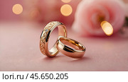 Gold wedding rings on a pink background with a side. Wedding rings. The wedding day. The newlyweds. Стоковое AI-изображение, AI-художник Photojuli / Фотобанк Лори