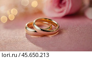 Gold wedding rings on a pink background with a side. Wedding rings. The wedding day. The newlyweds. Стоковое AI-изображение, AI-художник Photojuli / Фотобанк Лори