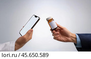Hands exchanging a medicine bottle and a smartphone in a neutral background. Стоковое AI-изображение, AI-художник Igor Tichonow / Фотобанк Лори