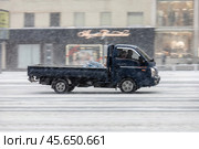 Small blue flatbed truck drive on winter street during snowstorm. Редакционное фото, фотограф Константин Григорьев / Фотобанк Лори