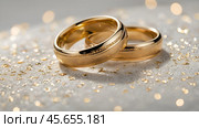 Gold wedding rings on a white background with a side. Wedding rings. The wedding day. The newlyweds. Стоковое AI-изображение, AI-художник Photojuli / Фотобанк Лори