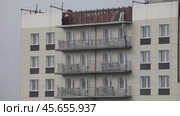 ANGARSK, IRKUTSK REGION, RUSSIA - October 08, 2024: Video of builders install light facade tiles on the top floor of a high-rise residential building. Urban residential construction concept. Редакционное видео, видеограф Виктория Катьянова / Фотобанк Лори