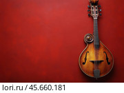 Red mandolin showcased against textured red wall in a cozy musical setting. Стоковое AI-изображение, AI-художник Юлия Гапеенко / Фотобанк Лори