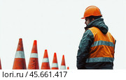 A road worker in a protective vest and an orange hard hat with red cones on a white background. Стоковое AI-изображение, AI-художник Ярославский Максим / Фотобанк Лори