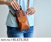 Крупным планом женские руки вынимают смартфон из маленькой кожаной сумки через плечо. Неузнаваемая женщина открывает сумочку из натуральной кожи. Концепция общения и образа жизни. Стоковое фото, фотограф Светлана Ельцова / Фотобанк Лори