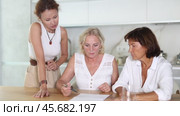 Three women help each other sort out financial documents in the kitchen of a home. Стоковое видео, видеограф Яков Филимонов / Фотобанк Лори