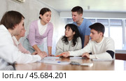 Cheerful young girl student discussing learning assignment with friendly coursemates gathered around table in classroom. Стоковое видео, видеограф Яков Филимонов / Фотобанк Лори