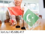 Young woman putting flags of China and Pakistan on table in office. Стоковое фото, фотограф Яков Филимонов / Фотобанк Лори
