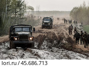 Военные грузовики и пехота вооружённых сил России движутся по дороге в лесу. Осенняя или весенняя распутица. Солдаты и военная техника. Логистика и ротация войск. (2019 год). Редакционное фото, фотограф Евгений Зимин / Фотобанк Лори