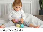 Cute baby girl playing tactile knobby balls. Young child hand plays sensory massage ball. Enhance the cognitive, physical process. Brain development. Support for Children with ADHD, autism, fidgeting. Стоковое фото, фотограф Марина Демидюк / Фотобанк Лори