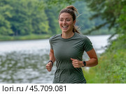 A girl in a green T-shirt is jogging along the river in the early summer morning. Стоковое AI-изображение, AI-художник Ярославский Максим / Фотобанк Лори