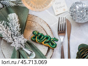 Stylish plates, napkin, glass, champagne, Christmas tree branches and Christmas decorations on a gray background. Table setting. The concept of Merry Christmas and New Year 2025. Стоковое фото, фотограф Photojuli / Фотобанк Лори