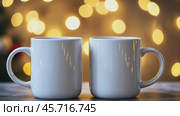 Christmas Mug Mock-Up. Two minimalistic white mugs. Blank white ceramic cups on a desk surface, beautiful warm bokeh lights blurred background. For overlaying your custom quotes, designs for selling. Стоковое AI-видео, аниматор Марина Демидюк / Фотобанк Лори