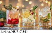 Festive Holiday Cocktails. Glasses of cocktails with Christmas decoration on bokeh lights background. Season drink set. Vibrant colorful display of various winter cocktails for New Year celebrations. Стоковое AI-видео, аниматор Марина Демидюк / Фотобанк Лори
