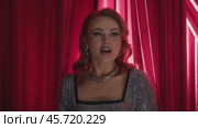 A professional singer sings her song standing in the classic red backstage and looking at the camera. Slow motion. Стоковое видео, видеограф Strunov David / Фотобанк Лори