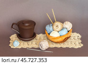Wooden bowl with skeins of natural cotton yarn for crocheting, crochet hooks and clay mug on handmade lace napkin on light brown background. Crochet as a hobby. DIY concept. Beautiful still life. Стоковое фото, фотограф Виктория Катьянова / Фотобанк Лори