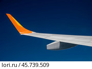 A plane wing extends against a deep blue sky. Travel concept. Стоковое фото, фотограф Ольга Губская / Фотобанк Лори