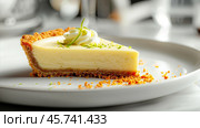 Slice of creamy key lime pie with a graham cracker crust, topped with whipped cream, lime zest, and a garnish, served on a white plate with crumb details. Стоковое AI-изображение, AI-художник Башкирова Анна / Фотобанк Лори