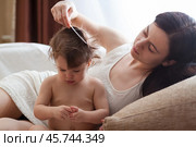 Молодая мать причесывает свою маленькую дочь с непослушными волосами. Стоковое фото, фотограф 1Andrey Милкин / Фотобанк Лори