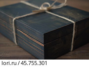 Elegant dark wooden keepsake box tied with string on table. Стоковое AI-изображение, AI-художник Иван Рябоконь / Фотобанк Лори