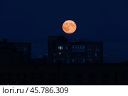 Super moon rising above city buildings. Night scene with big orange moon. Стоковое фото, фотограф Константин Григорьев / Фотобанк Лори